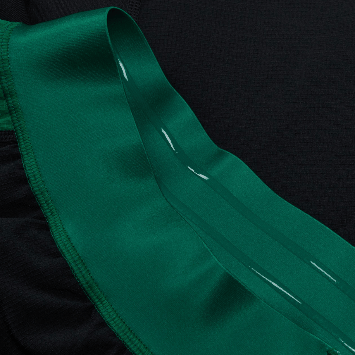 Close-up of the Ireland 24 Alternate Match Short by Canterbury in black and green, featuring a shiny green ribbon-like trim and crafted from durable stretch ripstop fabric.