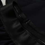 Close-up of a black garment featuring shiny, ruffled fabric and a smooth, satin-like ribbon detail, reminiscent of the premium quality found in the Ireland 24 Training Short by Canterbury.