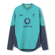 The Ireland 26 Tech Drill Top by Canterbury is a long-sleeved rugby jersey in teal and navy, inspired by IRFU training wear, with the Vodafone logo and IRFU crest on the chest, shown against a plain white background.