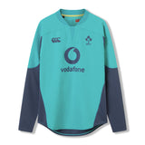 The Ireland 26 Tech Drill Top by Canterbury is a long-sleeved rugby jersey in teal and navy, inspired by IRFU training wear, with the Vodafone logo and IRFU crest on the chest, shown against a plain white background.