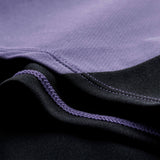 Close-up of fabric with black and purple sections, showing detailed stitching where the two colors meet—typical of premium training wear like the Ireland 26 Tech Drill Top by Canterbury.