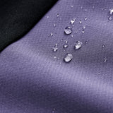 Close-up of water droplets on the purple Ireland 26 Tech Drill Top by Canterbury, with a black fabric corner, highlighting the water resistance and quality craftsmanship of Canterbury IRFU training wear.