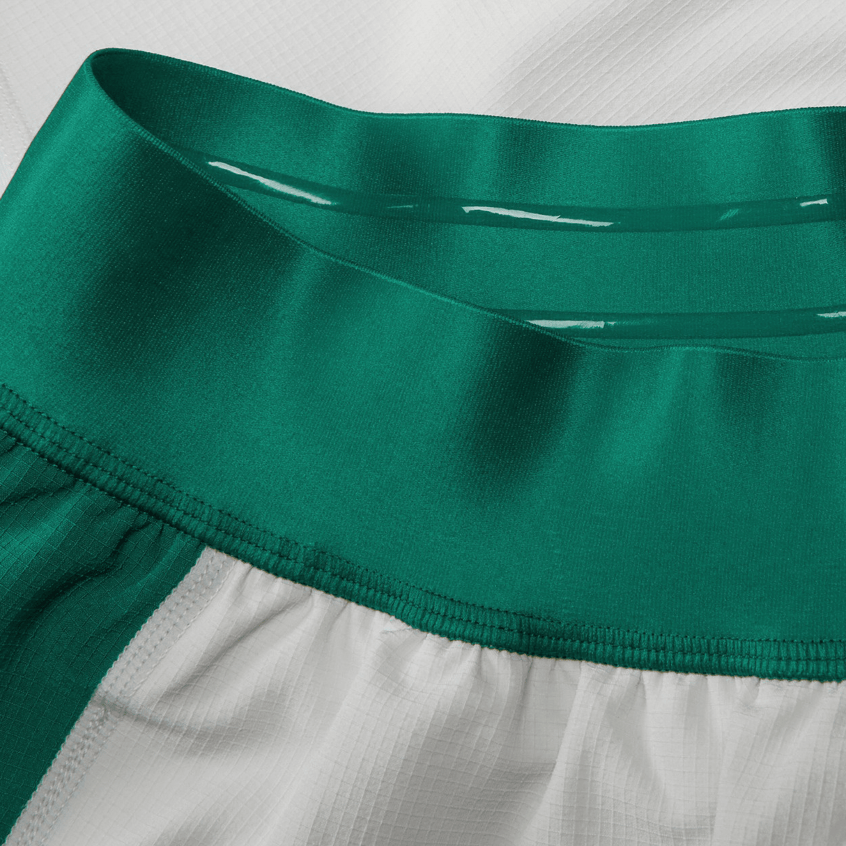 Close-up of the Junior Ireland 24 Home Match Short by Canterbury, featuring a green elastic waistband and white fabric with vertical green stripes, crafted from moisture-wicking material for enhanced comfort.