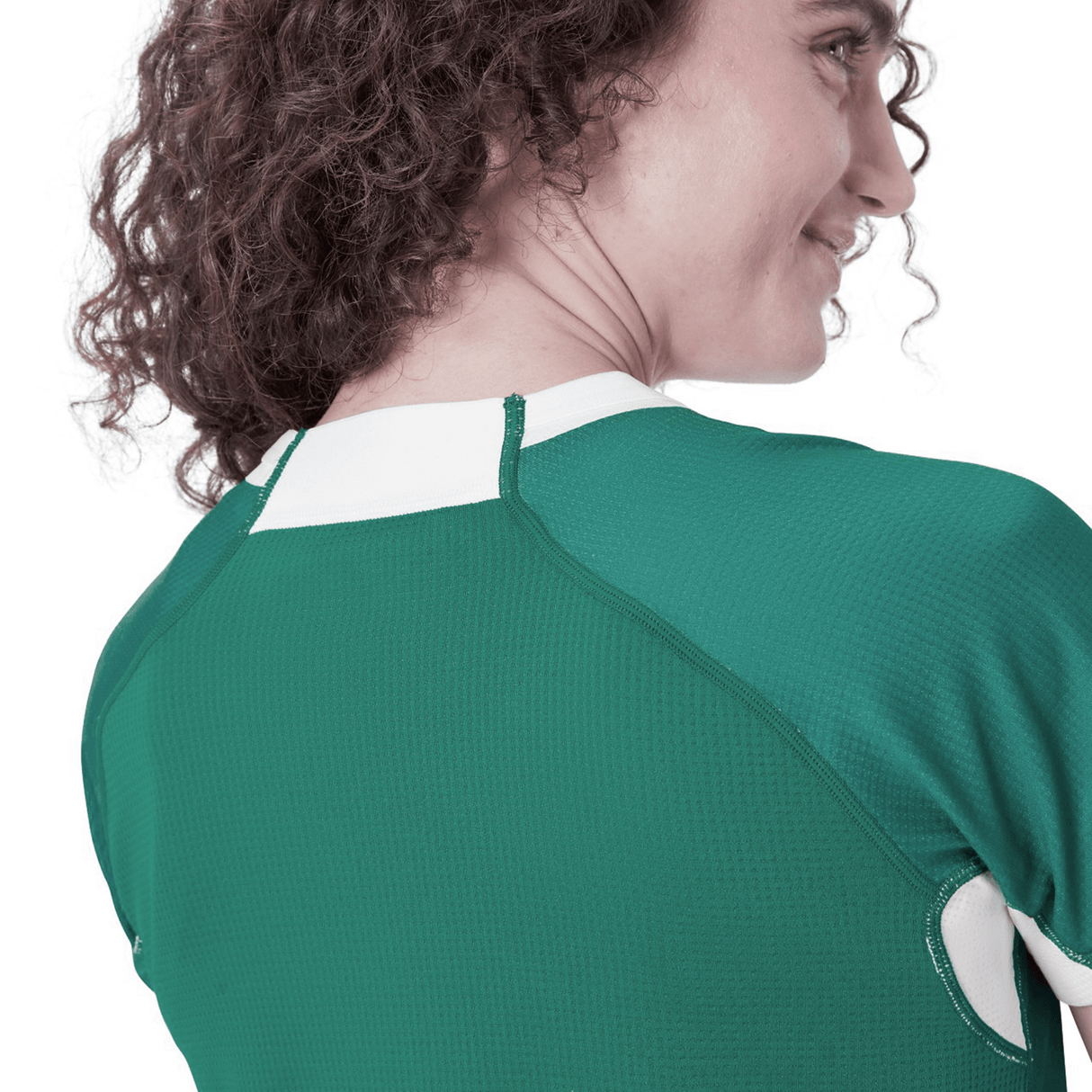 A person with curly hair is seen from behind wearing the Women's Ireland WIRFU Home Pro Jersey by Canterbury, displaying the Official IRFU crest in a chic green and white design.