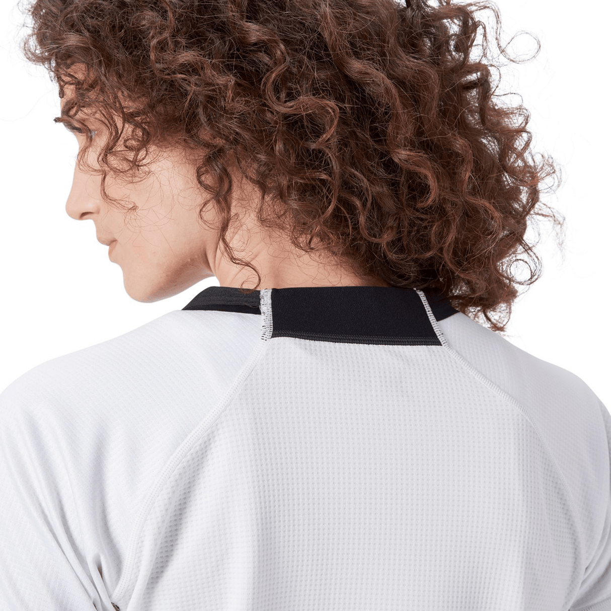 The person with curly hair is wearing a Women's Ireland 24 Alternate Pro Jersey by Canterbury, featuring a distinctive white shirt with black collar trim, viewed from the back.