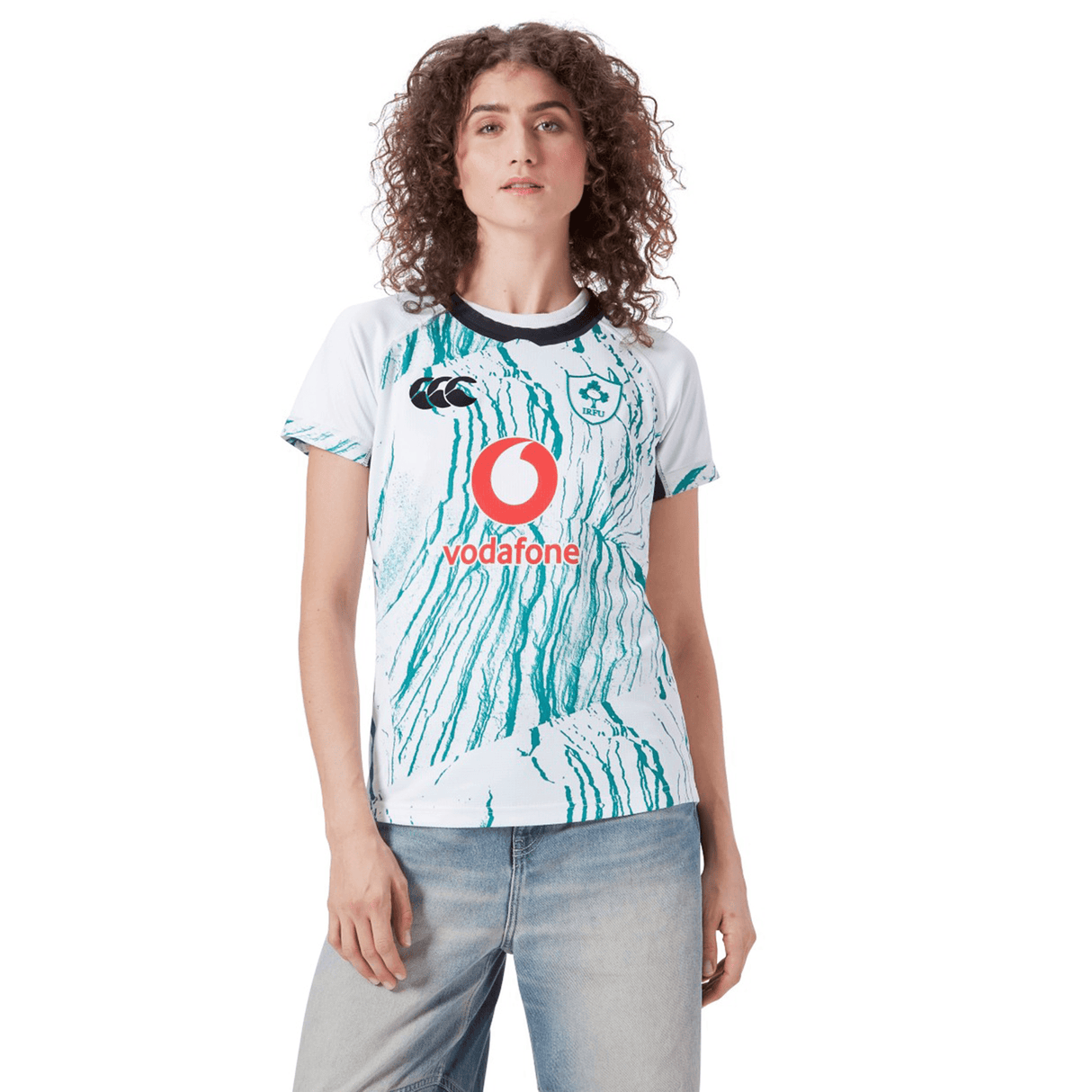 A person wears the Women's Ireland 24 Alternate Pro Jersey by Canterbury, featuring the IRFU Crest and Vodafone logo, paired with light blue jeans against a plain background.