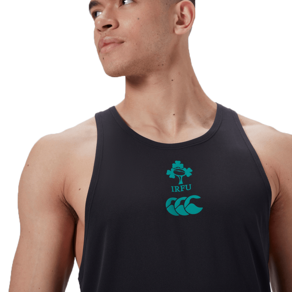 The individual wears the Ireland 24 Poly Training Singlet by Canterbury, a black sleeveless shirt featuring the IRFU logo with a shamrock and green text. Made from quick-drying fabric, it combines performance and style seamlessly.