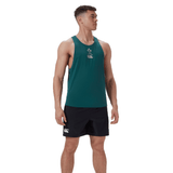 On a white background, a man stands with arms by his sides wearing the Ireland 24 Poly Training Singlet by Canterbury. The green sleeveless top with a clover design and quick-drying fabric is paired with black shorts, ideal for any setting.
