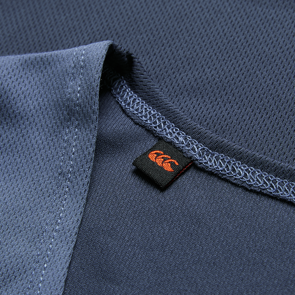 Close-up of the Ireland 26/27 Summer Tour Superlight Training Singlet by Canterbury, featuring detailed stitching and a small black tag with an orange logo.