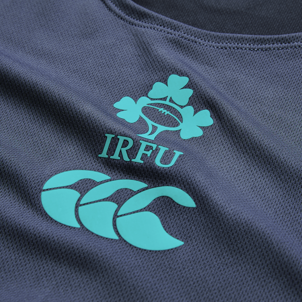 Close-up of the Ireland 26/27 Summer Tour Superlight Training Singlet by Canterbury, in dark blue, featuring the IRFU clover and Canterbury logos in teal—a lightweight design ideal for training.