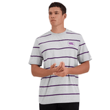 A man stands wearing a Canterbury Yarn Dye T-Shirt with purple horizontal stripes and the iconic Canterbury logo on the chest, looking to the side with his hands positioned in front of him.