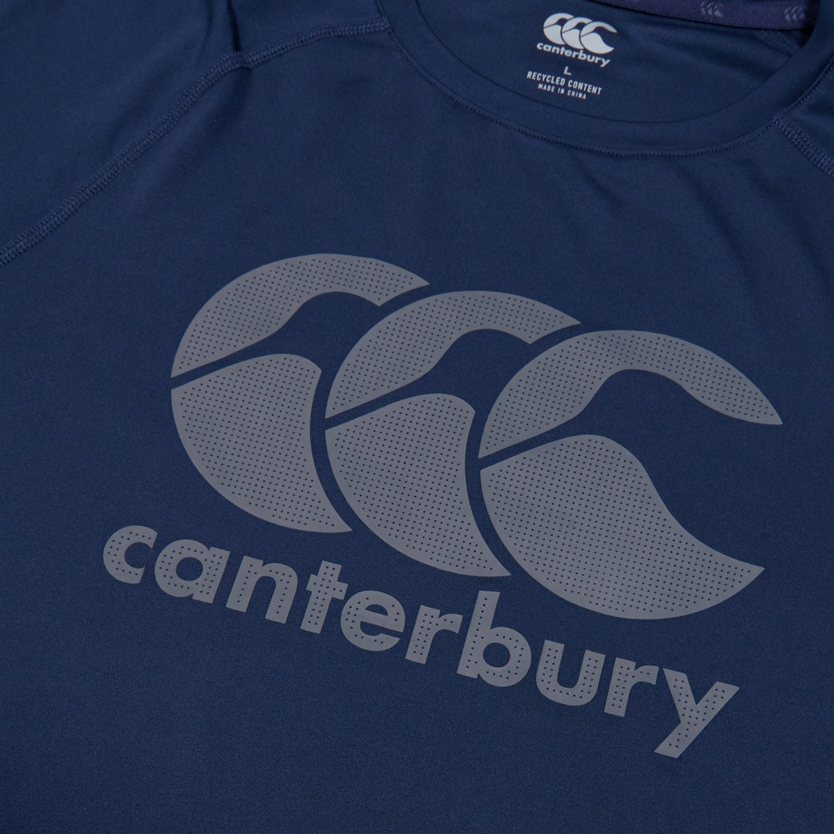 Close-up of the Canterbury Large Logo Superlight Tee AM in navy blue, a lightweight performance shirt with the Canterbury logo and brand name printed in grey on the chest.