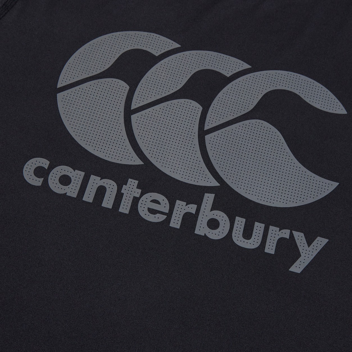 Close-up of the Canterbury Large Logo Superlight Tee AM, a dark training shirt with the Canterbury logo—three curved shapes—and "canterbury" in bold letters beneath.