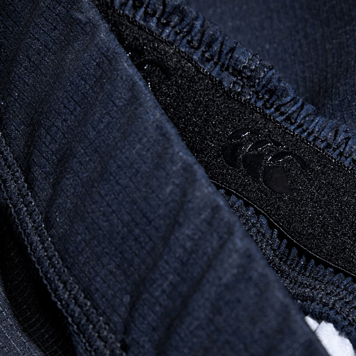 Close-up of the navy woven texture fabric and stitched seam of the Women's Canterbury Yokohama Short 3-Pack Bundle by Bundle Canterbury, showcasing a small black logo on a tag. This durable material is ideal for providing strength and reliability during women's intense rugby matches.