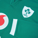 Close-up of the Ireland 25/26 Long Sleeve Classic Home Jersey by Canterbury, showcasing a green design with the IRFU logo—a shamrock and rugby ball—and a hint of red and white circular detail. Ideal for any Irish rugby fan to showcase their pride.