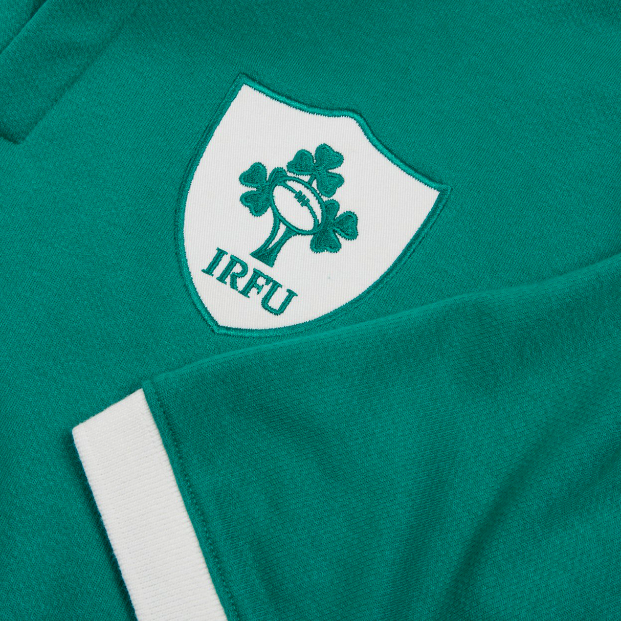 Close-up of the Ireland 25/26 Classic Home Jersey by Canterbury, highlighting the IRFU logo with a white shield, shamrocks, and rugby ball, plus a crisp white cuff.