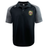 The RVA T.R.C. Elite Polo by Canterbury is a black and gray short-sleeve polo, crafted from lightweight and durable Vapodri fabrics. It features an “RVA” logo patch on the left chest and a small white EMB Canterbury logo on the right shoulder.