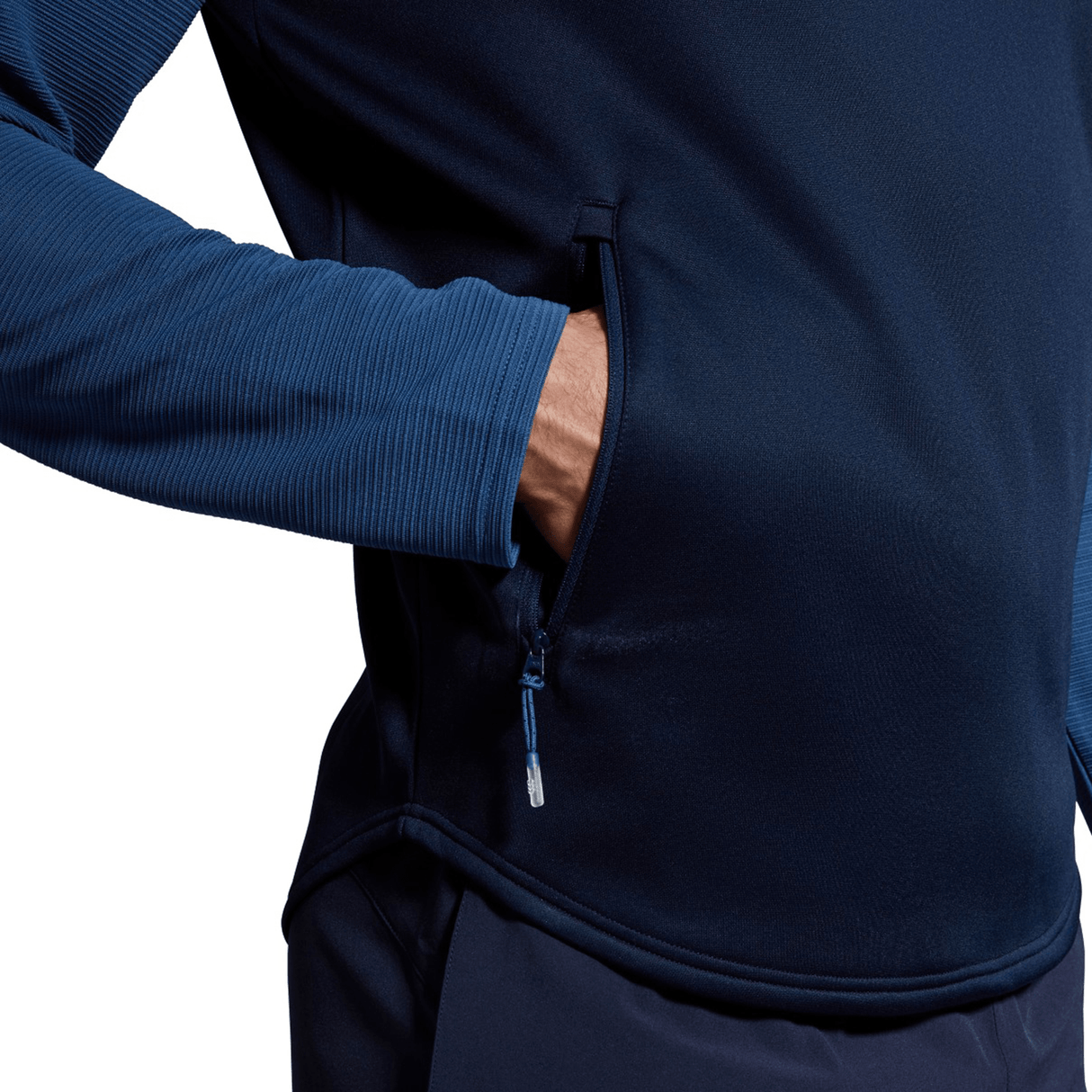 Man inserting hand into the zippered side pocket of a blue Canterbury Elite 1/4 Zip Top training jacket.