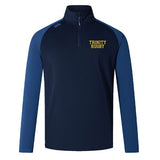A women's long-sleeve rugby top from EMB Canterbury, the Trinity College Women's Elite First Layer by Canterbury, in navy blue and light blue with "TRINITY RUGBY" text in yellow on the left chest, features VapoDri technology for superior moisture-wicking performance.