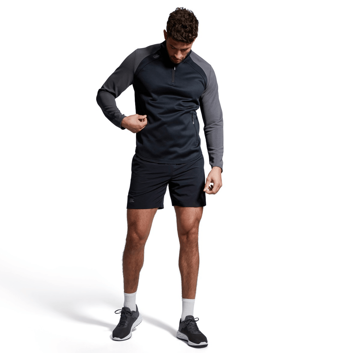 Man in Canterbury Elite 1/4 Zip Top looking at his smartwatch, standing against a white background.