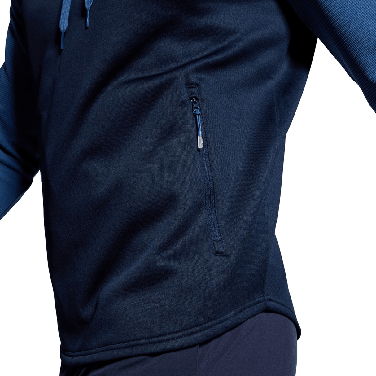Close-up of a person wearing the Canterbury Elite Training Hoodie in dark blue, showcasing the side pocket. Made from premium fabrics, this comfortable and versatile jacket keeps your arms slightly spread against a plain white background.