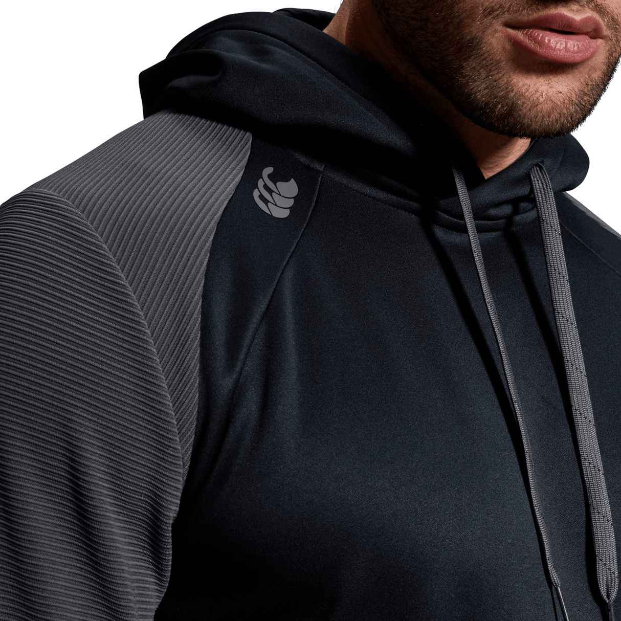 A person wearing a Canterbury Elite Training Hoodie with textured shoulders and drawstrings. The premium fabrics enhance the comfortable and versatile design, though the upper part of their face is not visible in the close-up shot.