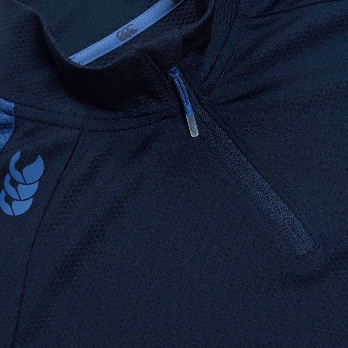 Close-up of a Women's Canterbury Elite First Layer, navy blue athletic top featuring a chest zipper and Canterbury logo, designed with VapoDri technology for enhanced performance, complemented by blue collar accents.
