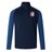 The Montgomery Bucks Griffins Women's Elite First Layer by EMB Canterbury is a navy and blue long-sleeve quarter-zip jacket with a stand collar, lion's head crest, and VapoDri tech for moisture wicking.