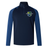 The Kingwood Rugby Elite First Layer by EMB Canterbury is a navy and blue quarter-zip pullover with a high collar and multicolored crest logo on the left chest, designed for rugby training.