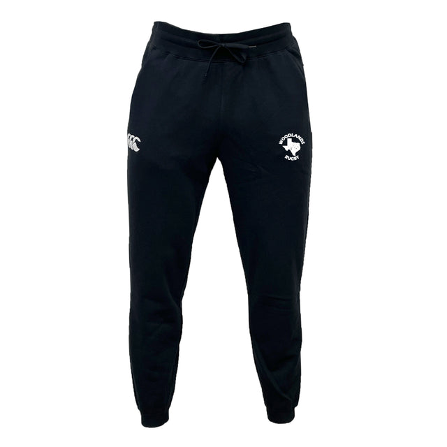 The Woodlands Rugby Leisure Sweatpant by EMB Canterbury are black joggers made from recycled polyester, featuring a drawstring waistband and two white front logos: "cc" and a shamrock with "Ireland Rugby." Stylish, sustainable leisurewear.