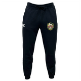 The EMB Canterbury RVA T.R.C. Leisure Sweatpant by Canterbury is a pair of black athletic pants with a drawstring waist, made from recycled polyester fleece, showcasing a white EMB Canterbury logo on the left thigh and a multicolored RVA soccer badge on the right thigh, displayed against a white background.