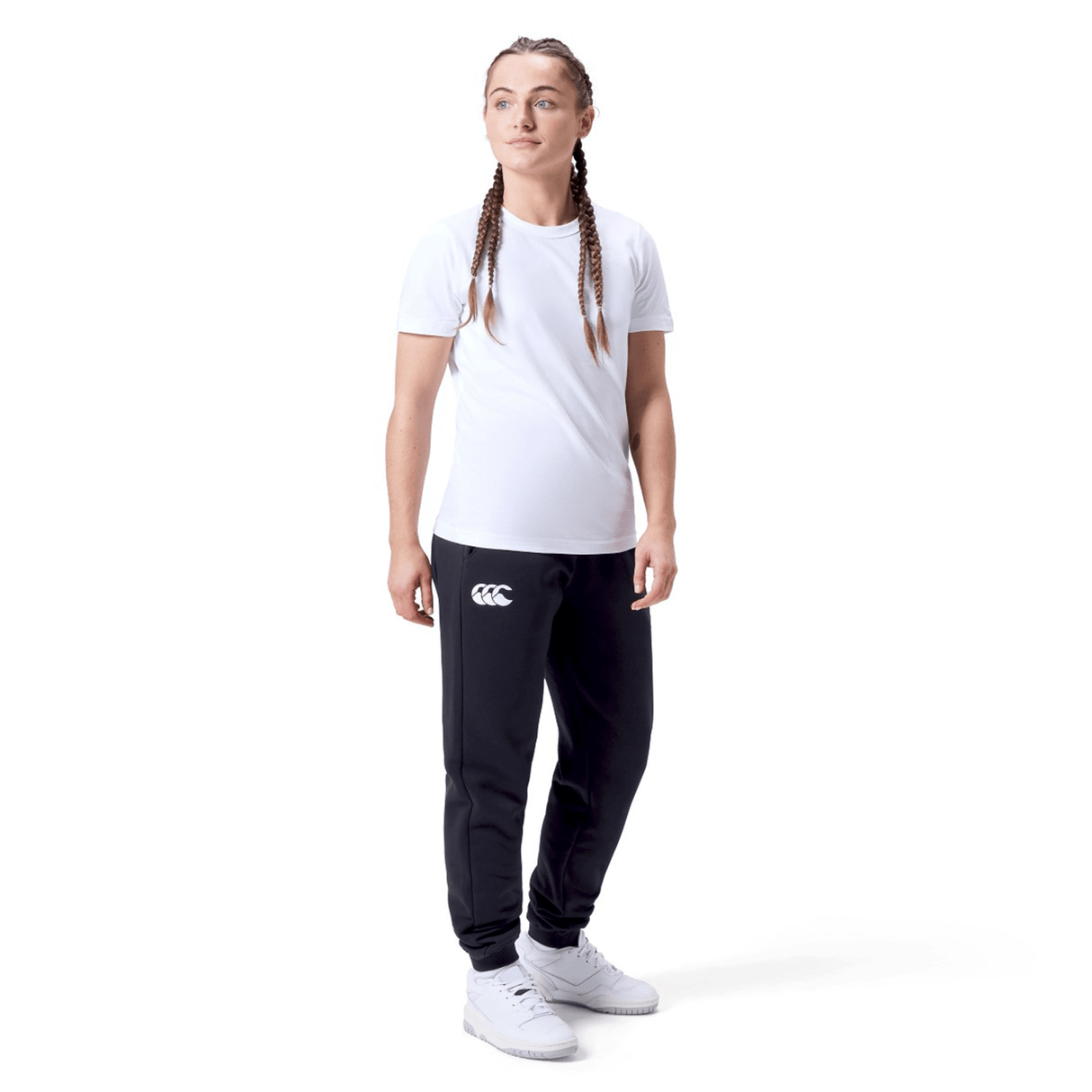 A person wears a white t-shirt, Women's Leisure Sweatpant by Canterbury in a cotton blend fleece, and white sneakers, standing against a plain white background.
