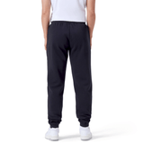 Rear view of a person wearing a white shirt, Women's Leisure Sweatpants by Canterbury, and white sneakers with the Canterbury logo, standing against a white background.