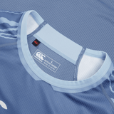 Close-up of a blue sports jersey collar with a Canterbury brand label indicating it is a size large made with recycled content, resembling the Ireland 24 Training Pro Jersey by Canterbury.