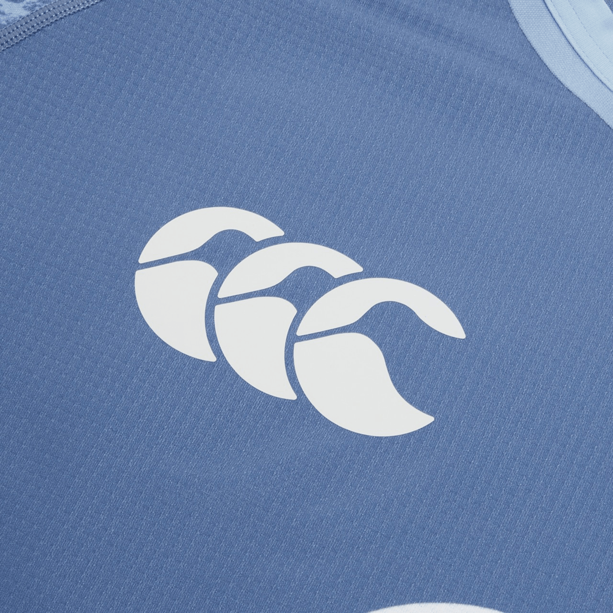 Close-up of the Ireland 24 Training Pro Jersey by Canterbury in blue, featuring a white Canterbury logo of three interlocking shapes resembling abstract waves.