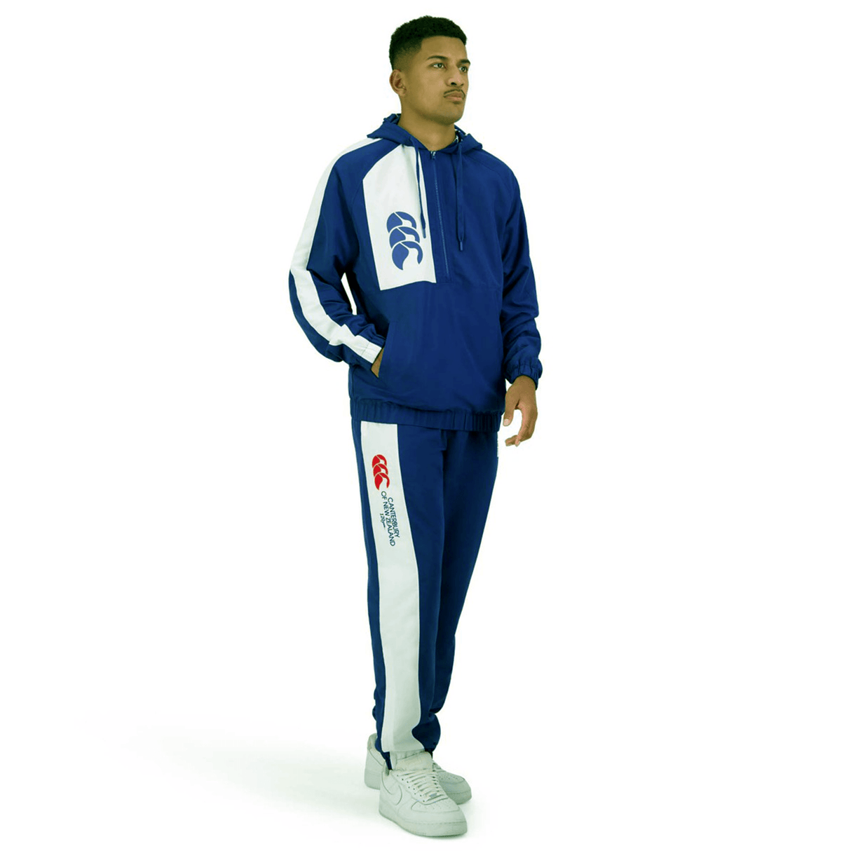 Person wearing a blue and white athletic tracksuit, standing against a plain white background. The tracksuit, identified as the Canterbury Legends Stadium Track Pant, features branded Canterbury logos on the chest and leg areas.