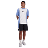 Man standing in a studio wearing a two-tone blue and white t-shirt, Canterbury Legends Panel Shorts with an elastic waistband, and white sneakers.