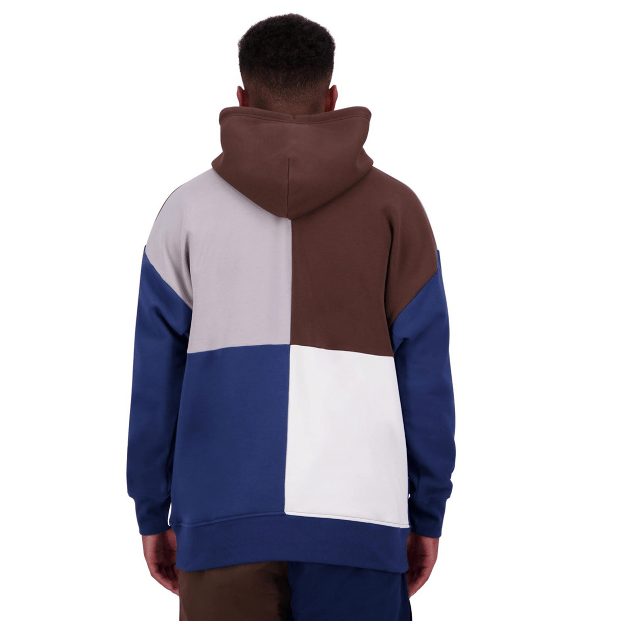 A person is wearing a Canterbury Harlequin Block Pullover Hoodie by Canterbury, featuring sections of brown, gray, navy blue, and white, while standing with their back to the camera.