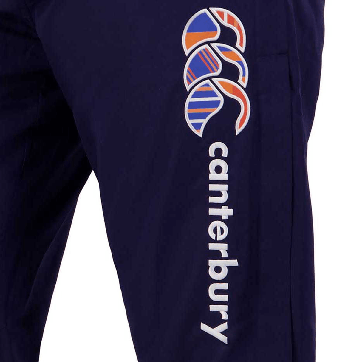 Close-up of the Canterbury Uglies Stadium Pants in navy blue, showcasing a colorful abstract design. The word "Canterbury" is printed on the side and the pants feature a stylish tapered leg.