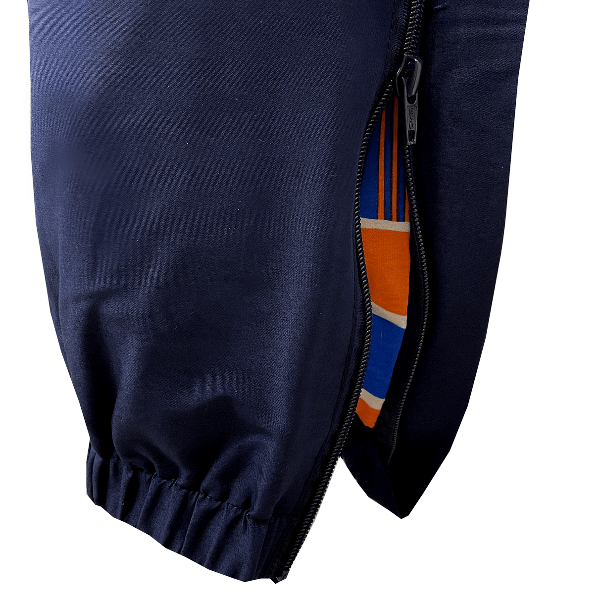 Close-up view of Canterbury's Uglies Stadium Pants, showcasing their tapered leg design and open zippered pocket, which reveals a lining accented with orange, blue, and white stripes in a stylish navy blue color.
