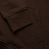 Close-up of a brown sweatshirt with ribbed cuffs and a side pocket, highlighted by bold colors reminiscent of the Canterbury Uglies Hoodie by Canterbury.