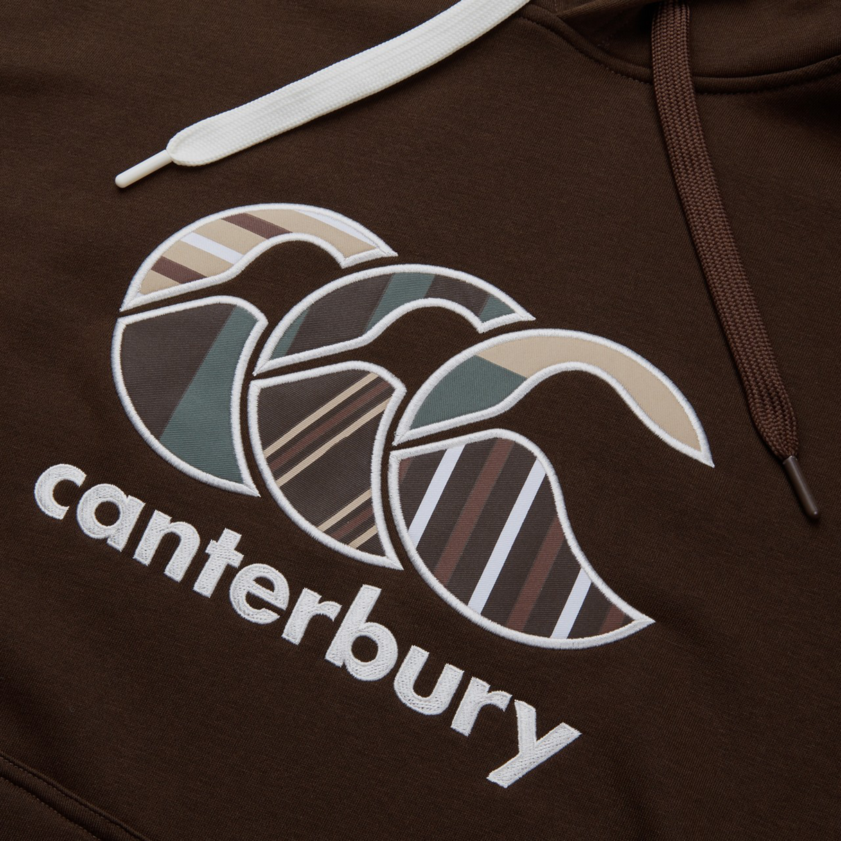 The Canterbury Uglies Hoodie features a bold stylized CCC logo in block colors, enhanced by earth-tone patterns.