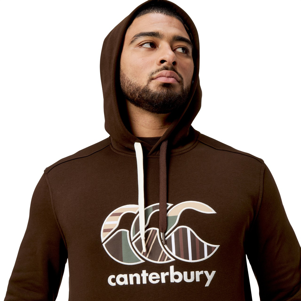 A man proudly gazes upward, showcasing the bold block-colored Canterbury Uglies Hoodie adorned with the stylized CCC logo.