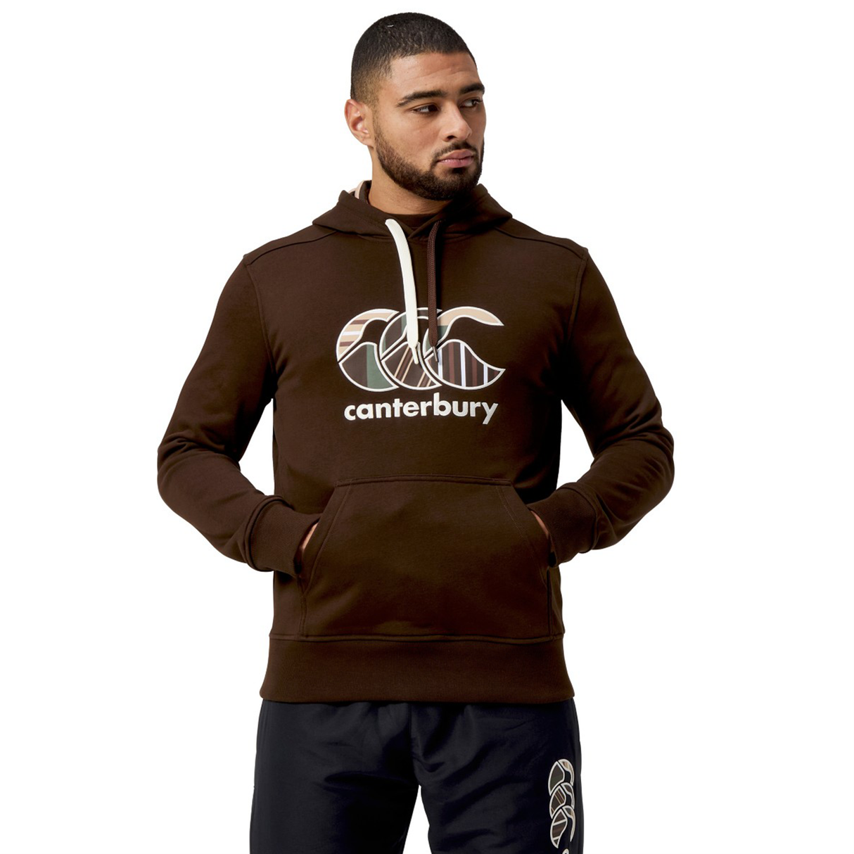A man in a Canterbury Uglies Hoodie, featuring the stylized CCC logo, stands with hands in pockets.