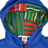 The Canterbury Uglies Hoodie has a blue exterior with bold block colors inside the hood's multicolored striped lining. A white "Canterbury" label at the hood's base and a stylized CCC logo enhance its vibrant look.