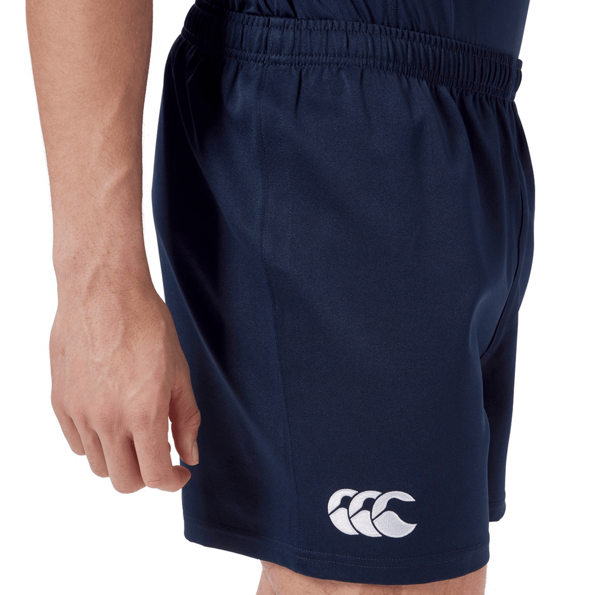 A person wearing Canterbury’s Professional Short 2.0, dark blue athletic shorts with an elastic waistband and a white Canterbury logo on the left leg, designed for comfort and durability.