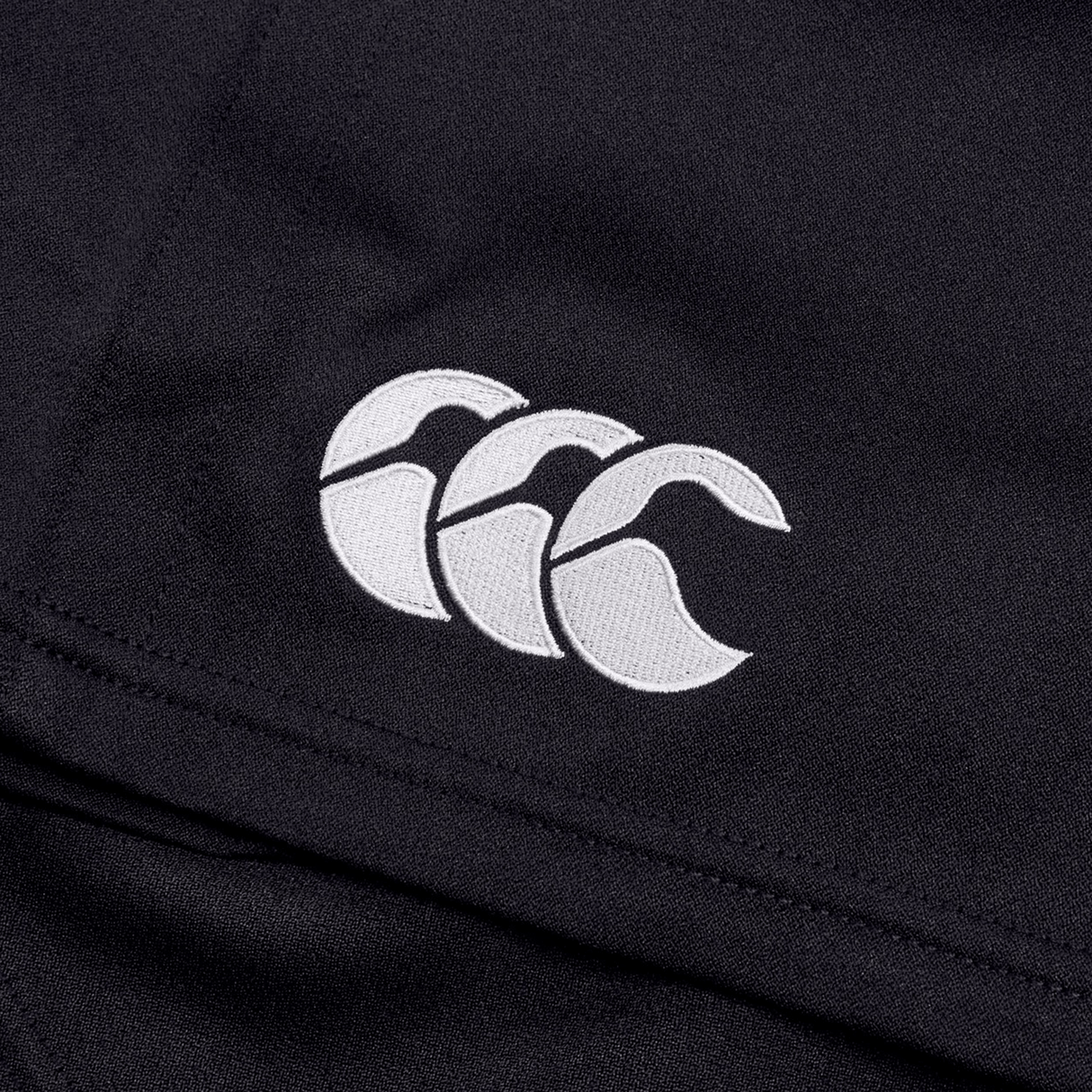 Close-up of black fabric featuring a white embroidered Canterbury logo with three overlapping C's, emphasizing the durability of the Canterbury Professional Short 2.0.