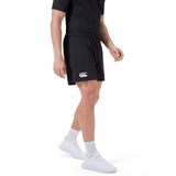 Someone is wearing Canterbury's black Professional Short 2.0, a black T-shirt, white socks, and white sneakers while standing against a plain background.