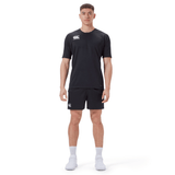 A man faces forward wearing the Canterbury Professional Short 2.0 in black, a black short-sleeve athletic shirt, white socks, and white athletic shoes against a plain white background.