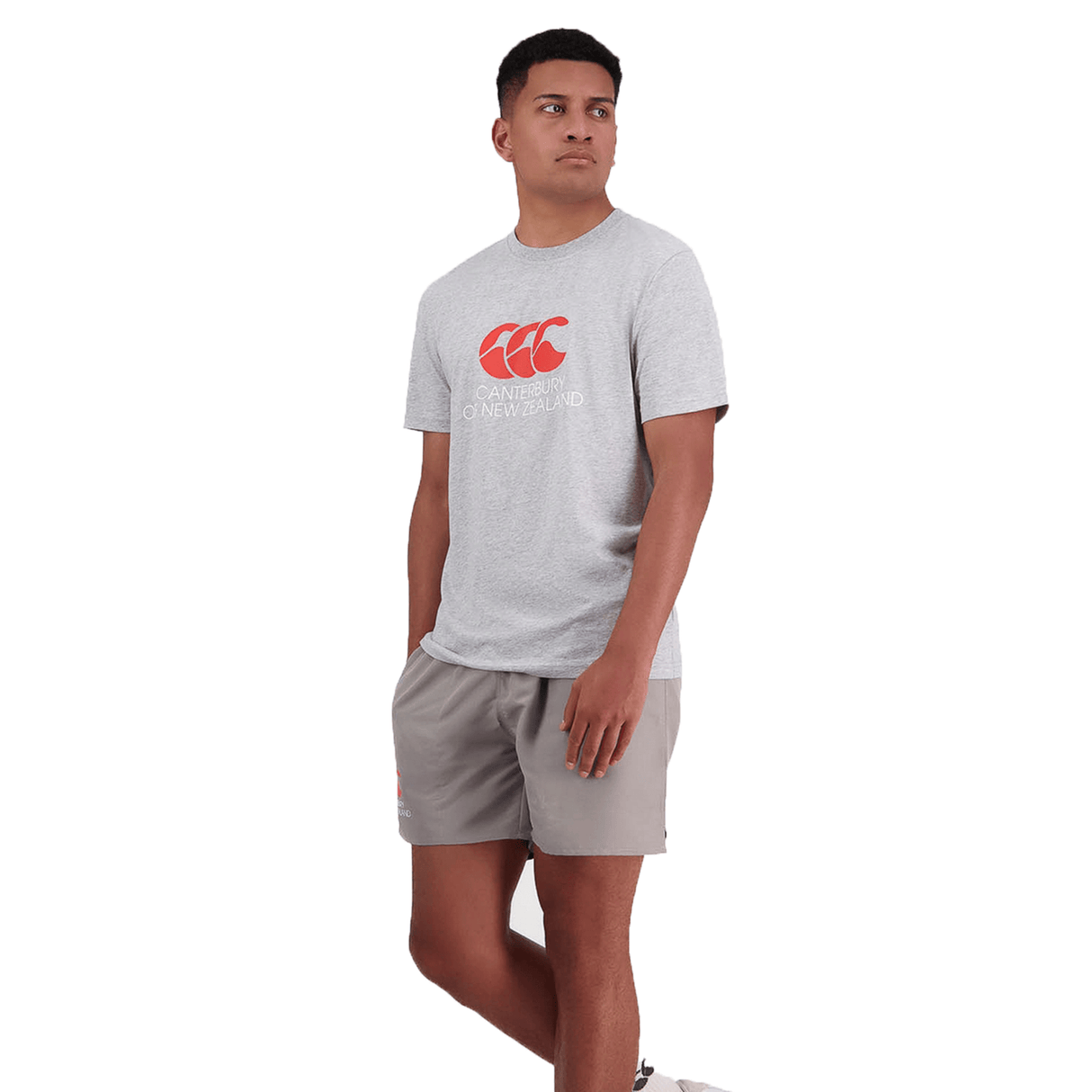 A person stands wearing a grey Canterbury of New Zealand Logo T-Shirt by Canterbury and matching grey shorts against a plain white background.